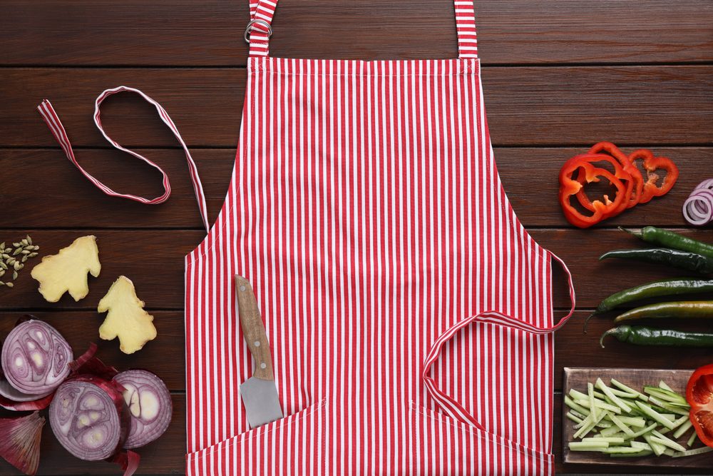 Flat lay composition with striped apron and different ingredients on wooden table