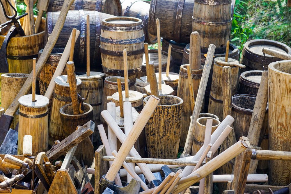 Authentic old wooden barrels of various sizes with metal hoops, butter churns, wooden utensils