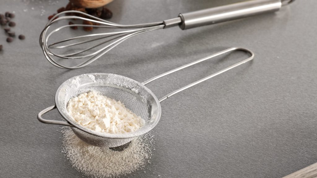 Sieve with flour on gray table