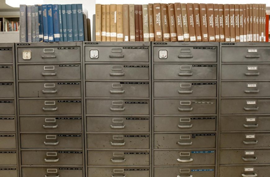 Organized filing cabinets stacked with indexed books in a library setting.