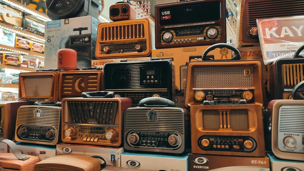 A variety of retro and vintage radios stacked in an indoor store, showcasing nostalgia.