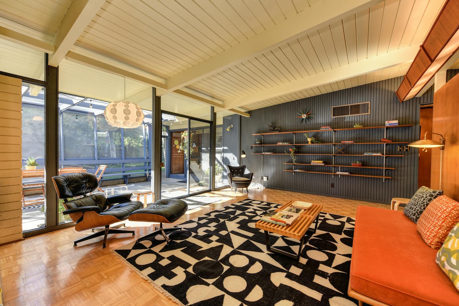 Stylish mid-century modern living room with armchairs, shelves, and natural light.