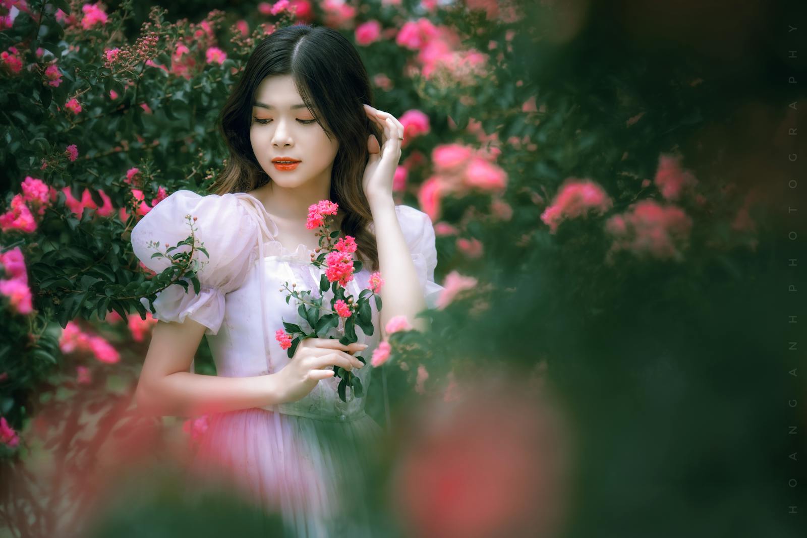 A woman gracefully poses amidst vibrant flowers in a serene summer garden.