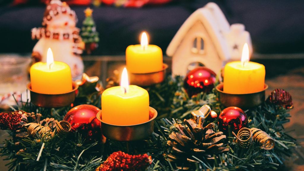 Cozy Christmas display featuring candles, ornaments, and festive wreath in warm candlelight.
