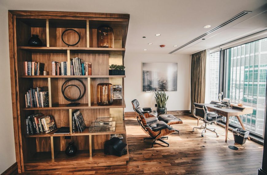 Stylish office space featuring a wooden bookshelf and a minimalist desk setup, ideal for work.