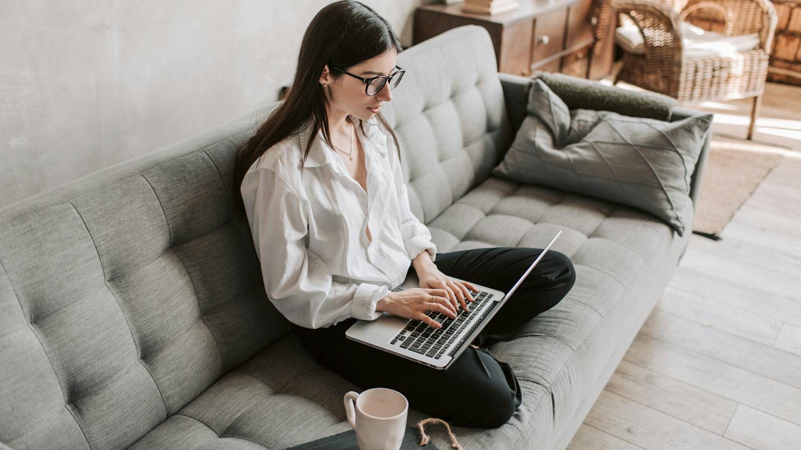 Woman in a cozy home setting working on a laptop for remote work and relaxation.