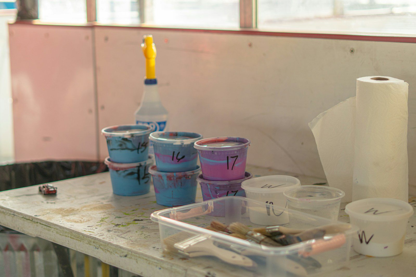 Paints, brushes, and supplies are on a work table.