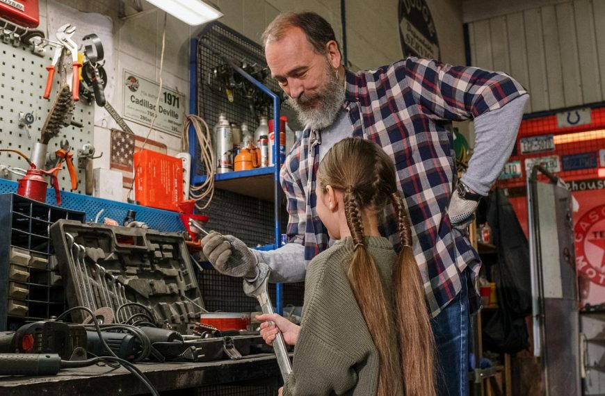 A father and daughter bonding over tools in an auto repair workshop, in a warm family moment.