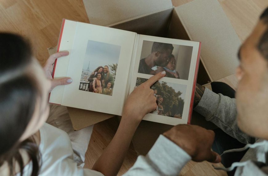 A couple reminisces over a photo album while unpacking during a move into their new home.