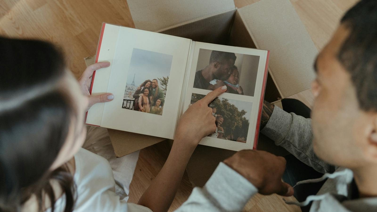 A couple reminisces over a photo album while unpacking during a move into their new home.