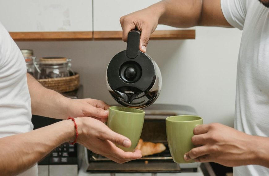 Two adults sharing a warm moment pouring coffee in a cozy kitchen.