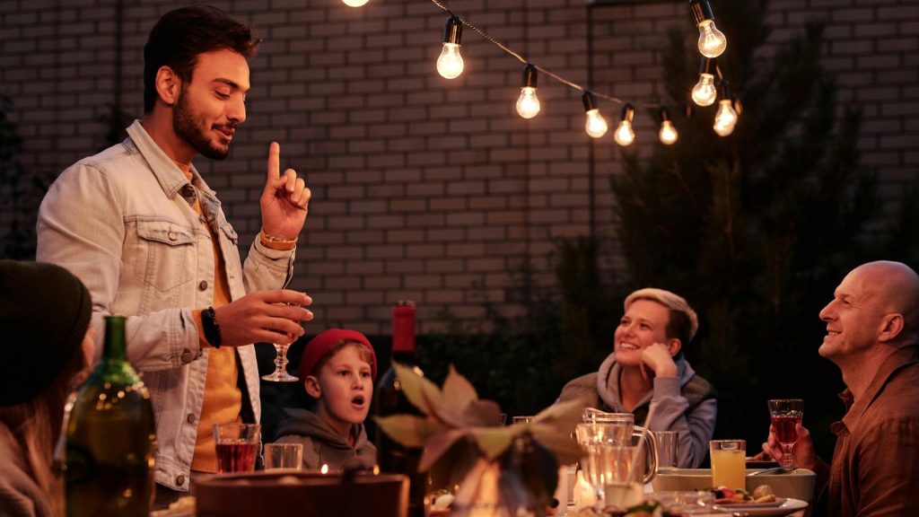 A cheerful group enjoying a festive evening gathering with lights and drinks.