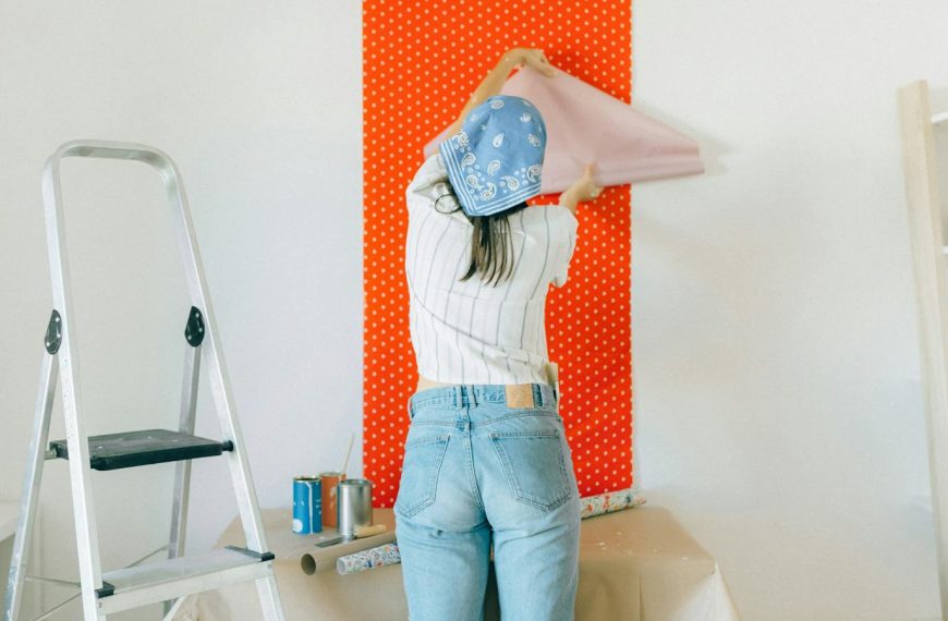 A woman applies polka dot wallpaper during a home makeover, showcasing DIY renovation.