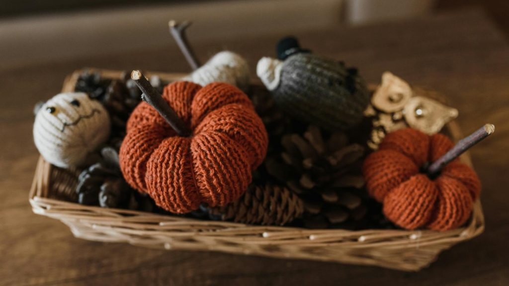 A charming basket of knitted Halloween decorations, perfect for a cozy autumn atmosphere.