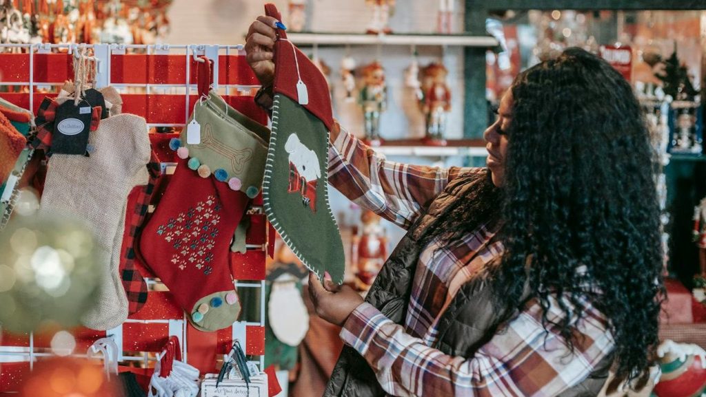Side view of smiling African American female with Xmas sock in shop with decorative baubles and gifts