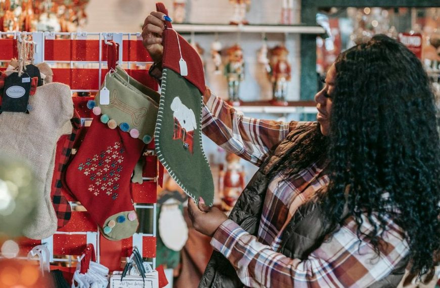 Side view of smiling African American female with Xmas sock in shop with decorative baubles and gifts