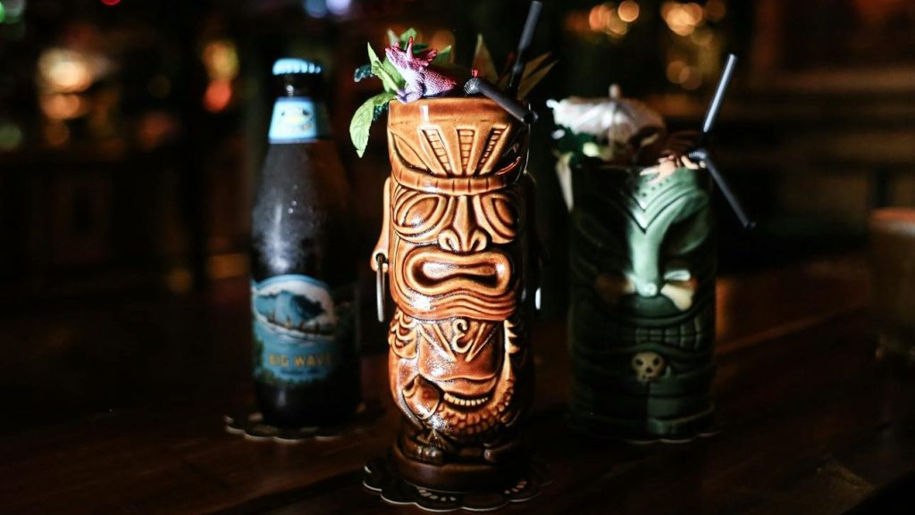 Vibrant tiki cocktails with bokeh lights in a cozy bar. Perfect for festive gatherings and exotic drinks.