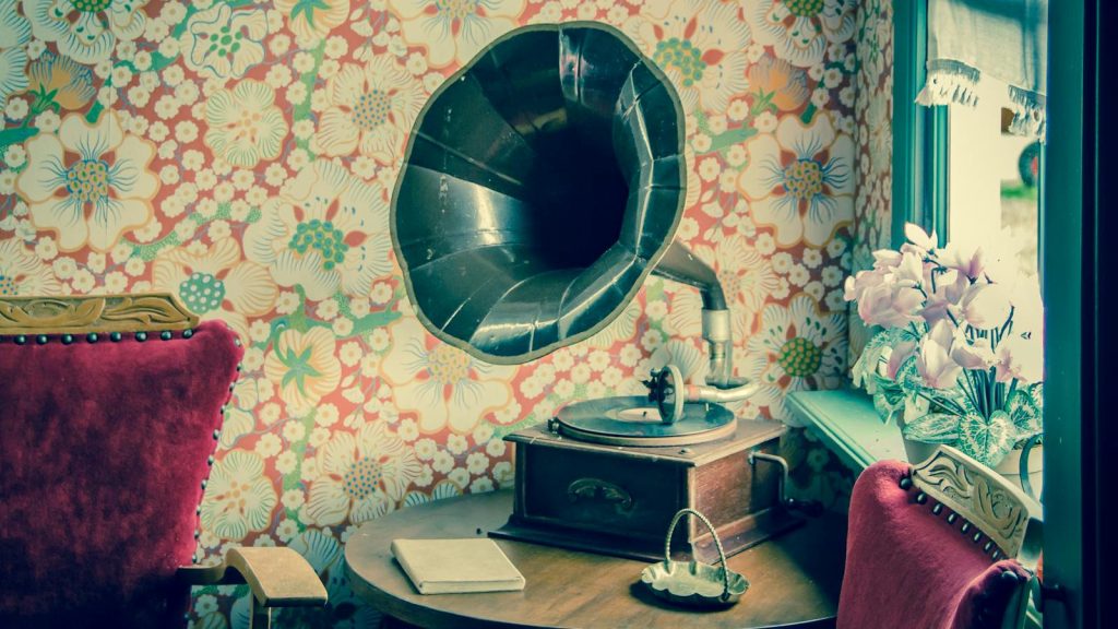 Retro gramophone in a room with floral wallpaper and vintage decor.