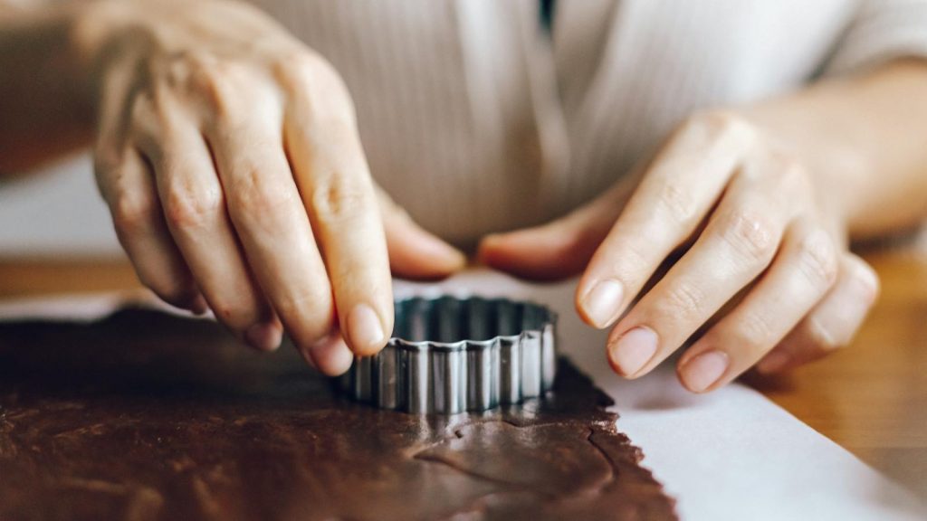 Hands using a cutter for making chocolate cookies at home. Perfect for baking articles and home-cooking themes.