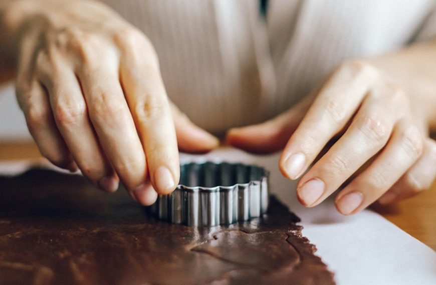 Hands using a cutter for making chocolate cookies at home. Perfect for baking articles and home-cooking themes.