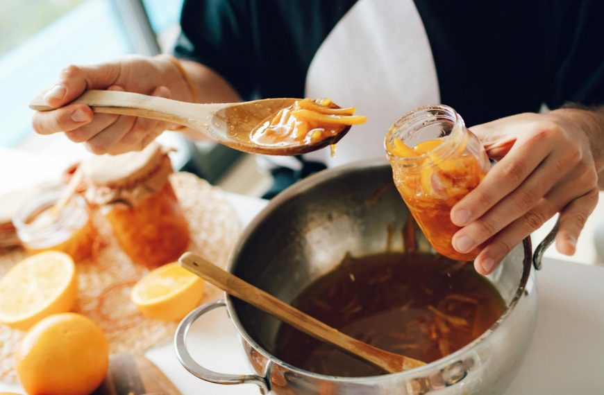 Close-up of hands making homemade orange marmalade in the kitchen.