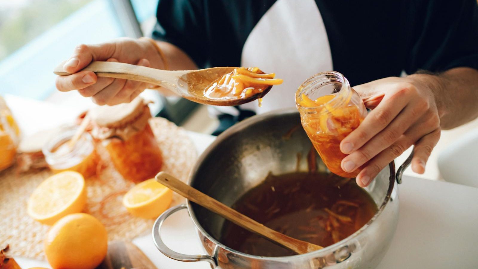 Close-up of hands making homemade orange marmalade in the kitchen.