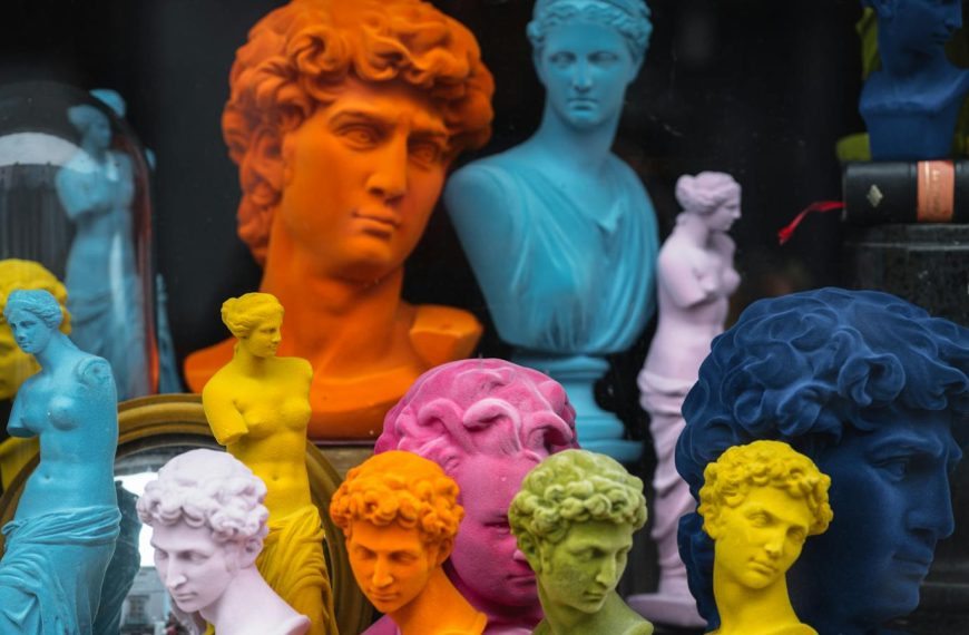 Multicolored head sculptures of David near bright statuettes placed in store with abundance of souvenirs and black pillar with book