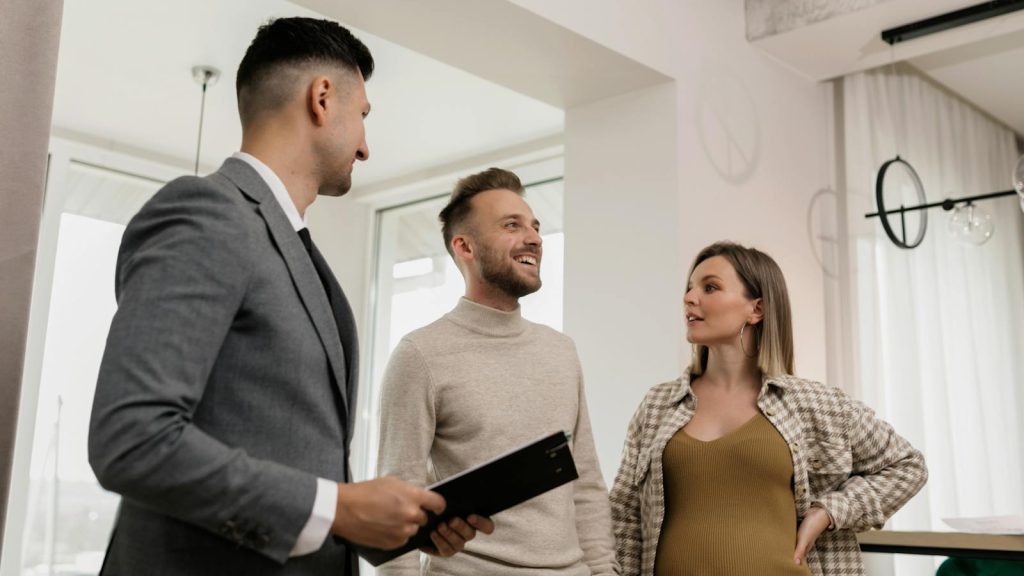 A couple consults with a real estate agent indoors, showcasing an exemplary customer service moment.