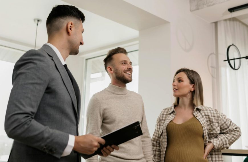 A couple consults with a real estate agent indoors, showcasing an exemplary customer service moment.