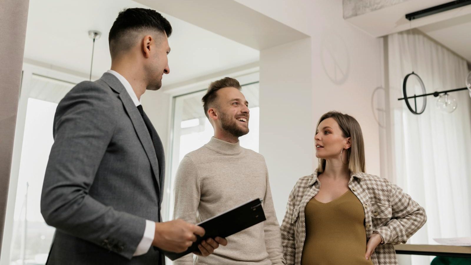 A couple consults with a real estate agent indoors, showcasing an exemplary customer service moment.