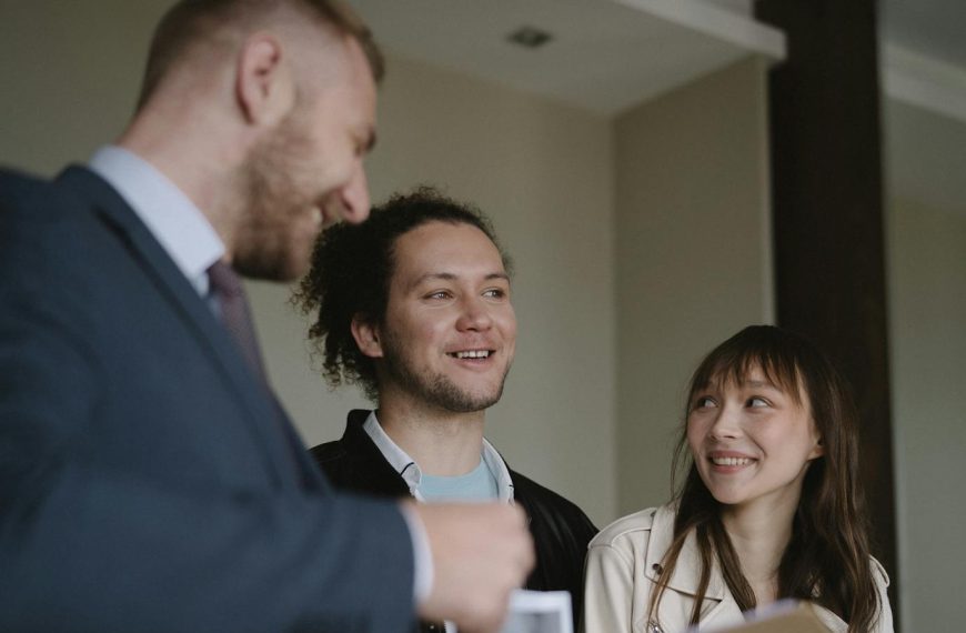 Happy young couple conversing with a realtor indoors about a new apartment.