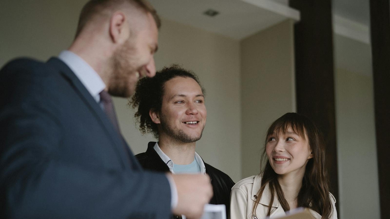 Happy young couple conversing with a realtor indoors about a new apartment.