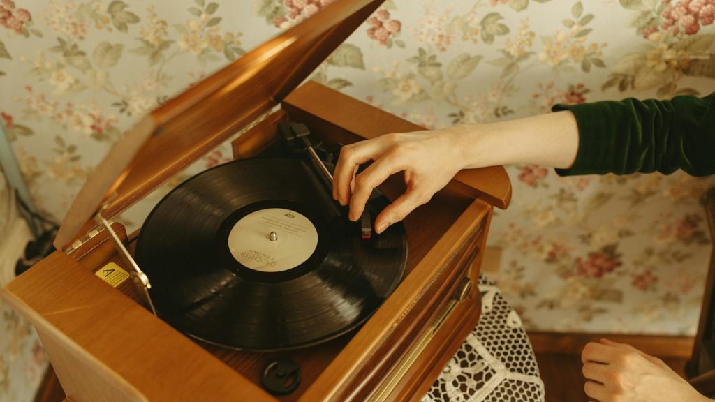 Hand playing a vinyl record on a vintage turntable in a retro styled room.