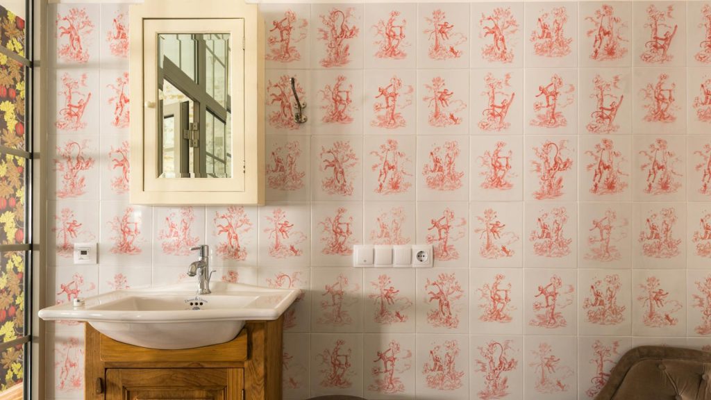 Charming vintage bathroom interior with patterned tiles, wooden sink cabinet, and mirror.