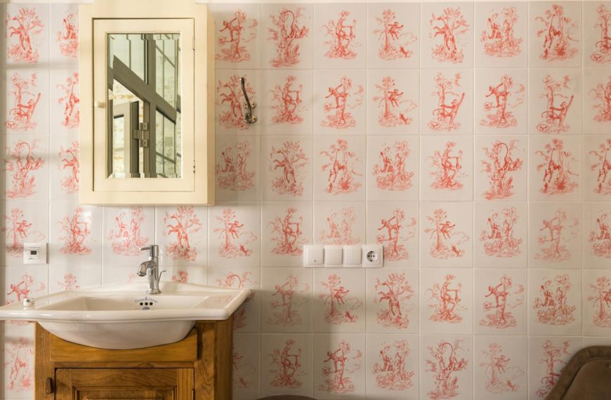 Charming vintage bathroom interior with patterned tiles, wooden sink cabinet, and mirror.
