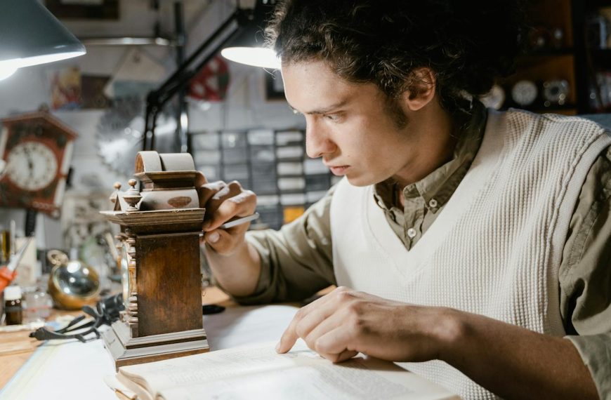 Focused young watchmaker meticulously working on a clock repair in a cluttered workshop.