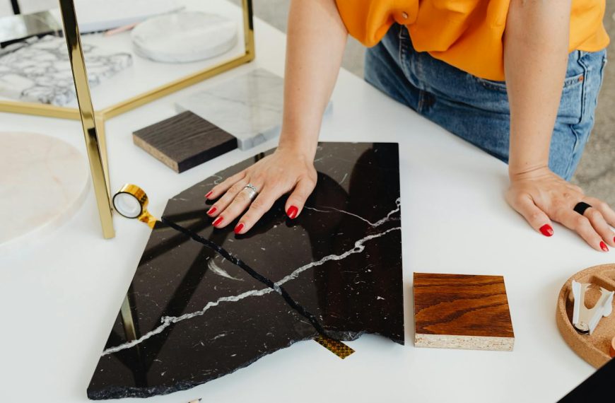 Designer reviews marble samples on white desk, highlighting hands and materials.