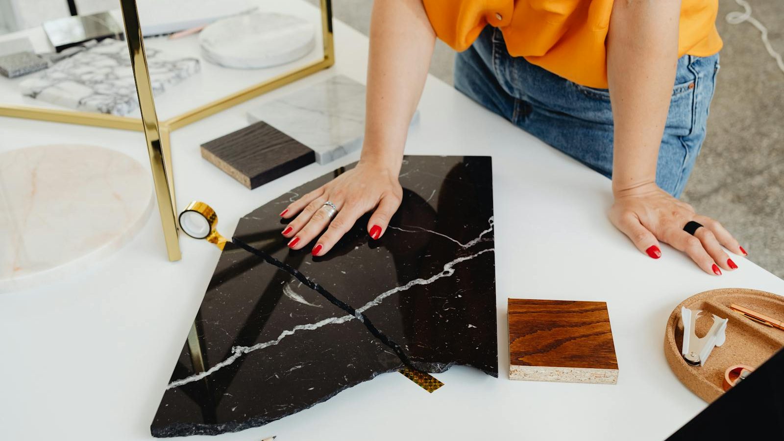 Designer reviews marble samples on white desk, highlighting hands and materials.