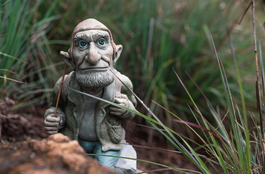 A charming garden gnome figurine sits nestled in vibrant grasses, adding whimsy to the outdoor space.