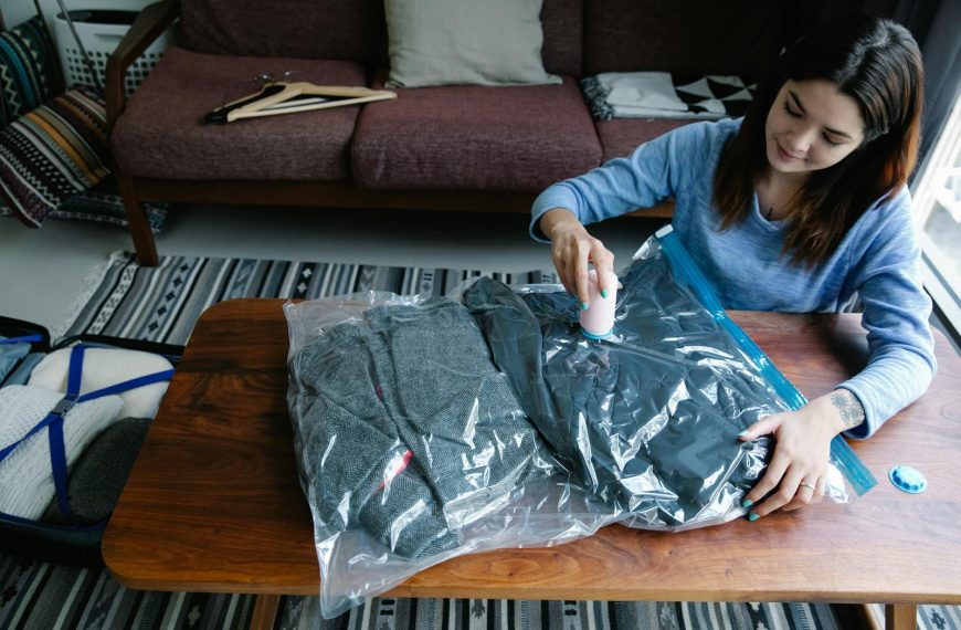 Woman sealing clothes in vacuum bags for efficient packing at home.