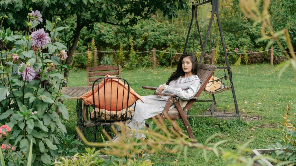 A woman lounging in a garden surrounded by lush greenery and colorful flowers.