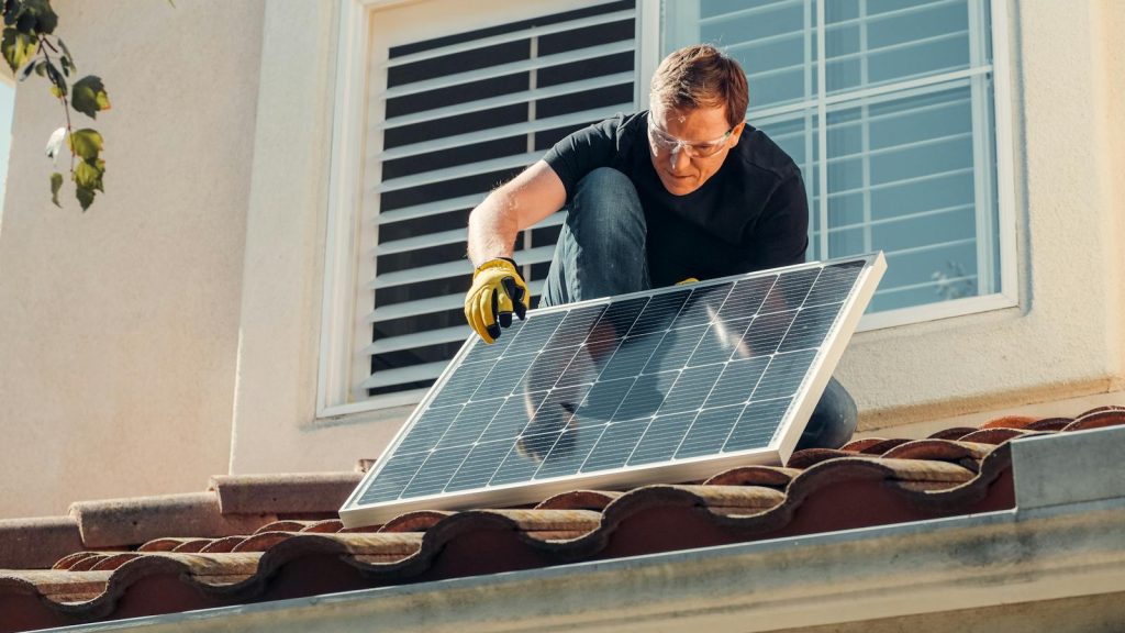 Solar technician installing a photovoltaic panel on a rooftop, promoting renewable energy.