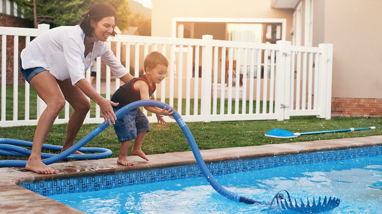 Fun times by the pool. Shot of a mother and son cleaning the pool together