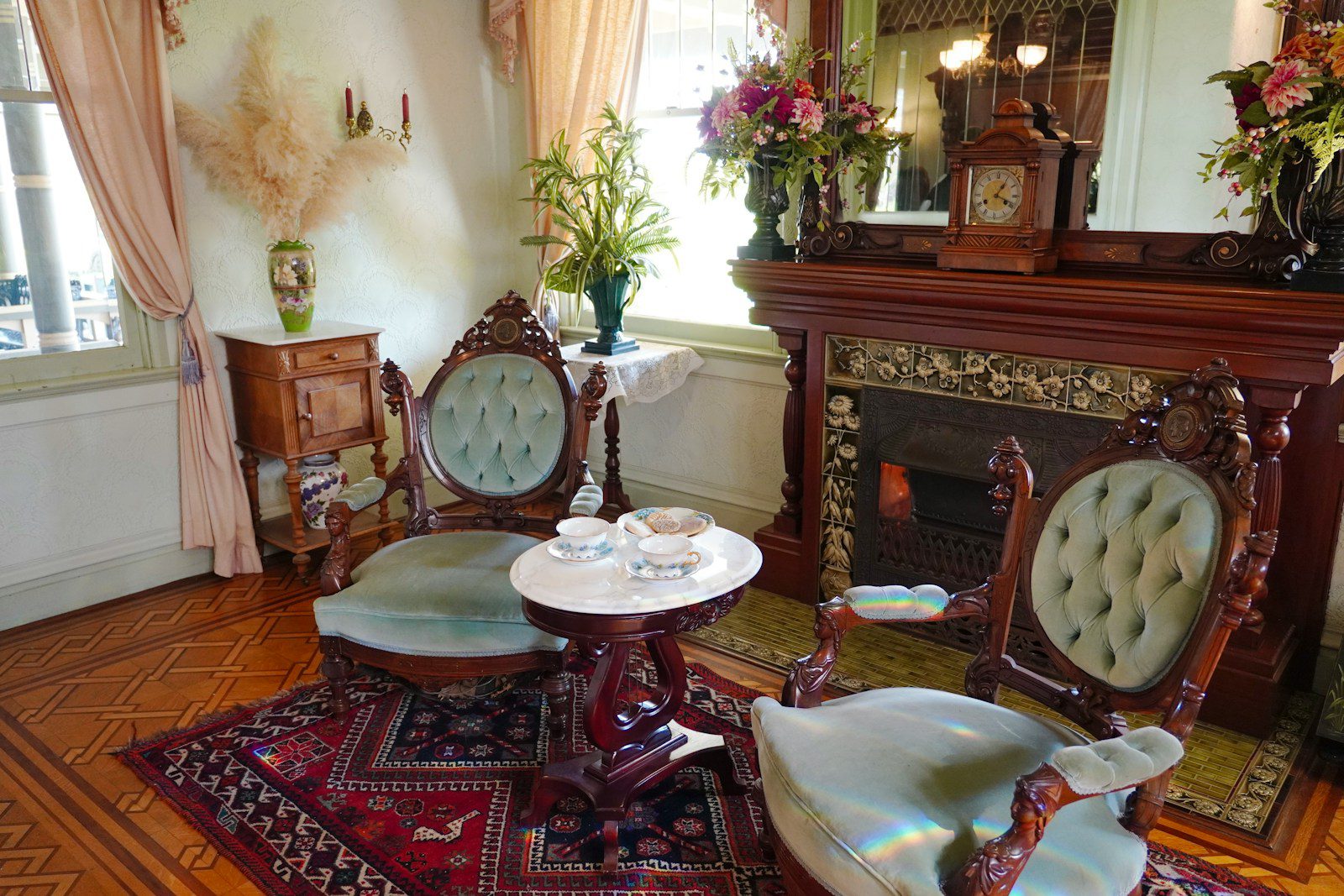 An antique parlor features chairs and a fireplace.
