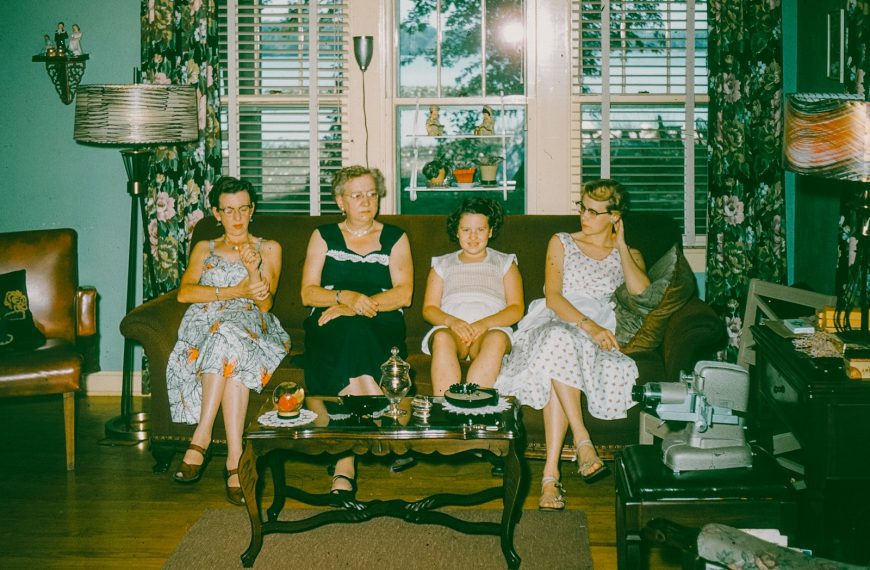 Four women sitting on a couch in a living room.
