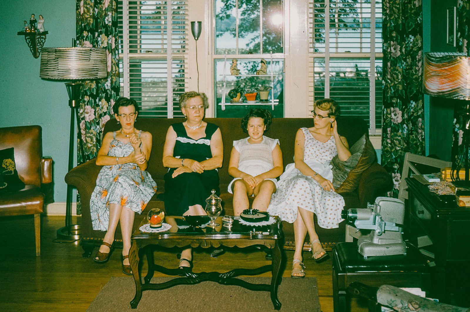 Four women sitting on a couch in a living room.