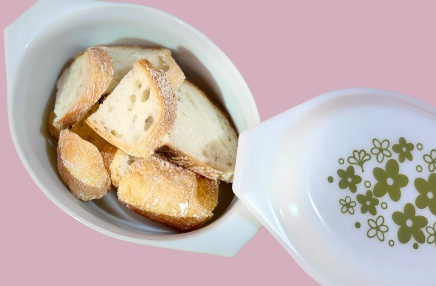 A white bowl filled with food on top of a pink table