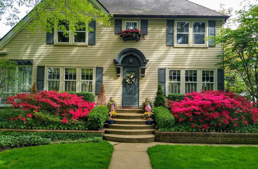 gray concrete house with red flowers on the side