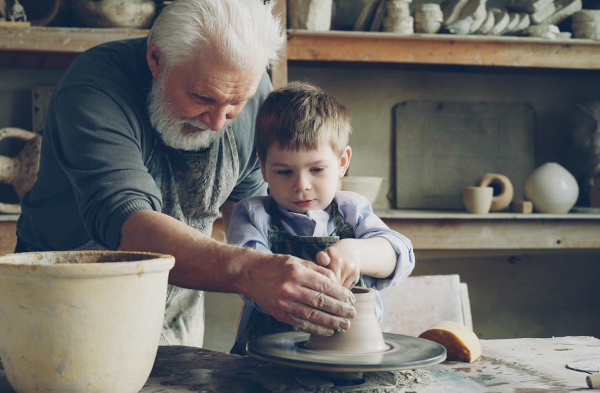 A grandfather teaches a child how to make pottery.