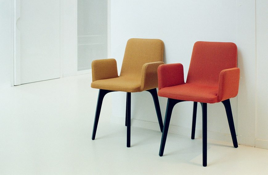Two colorful chairs sit against a white wall.